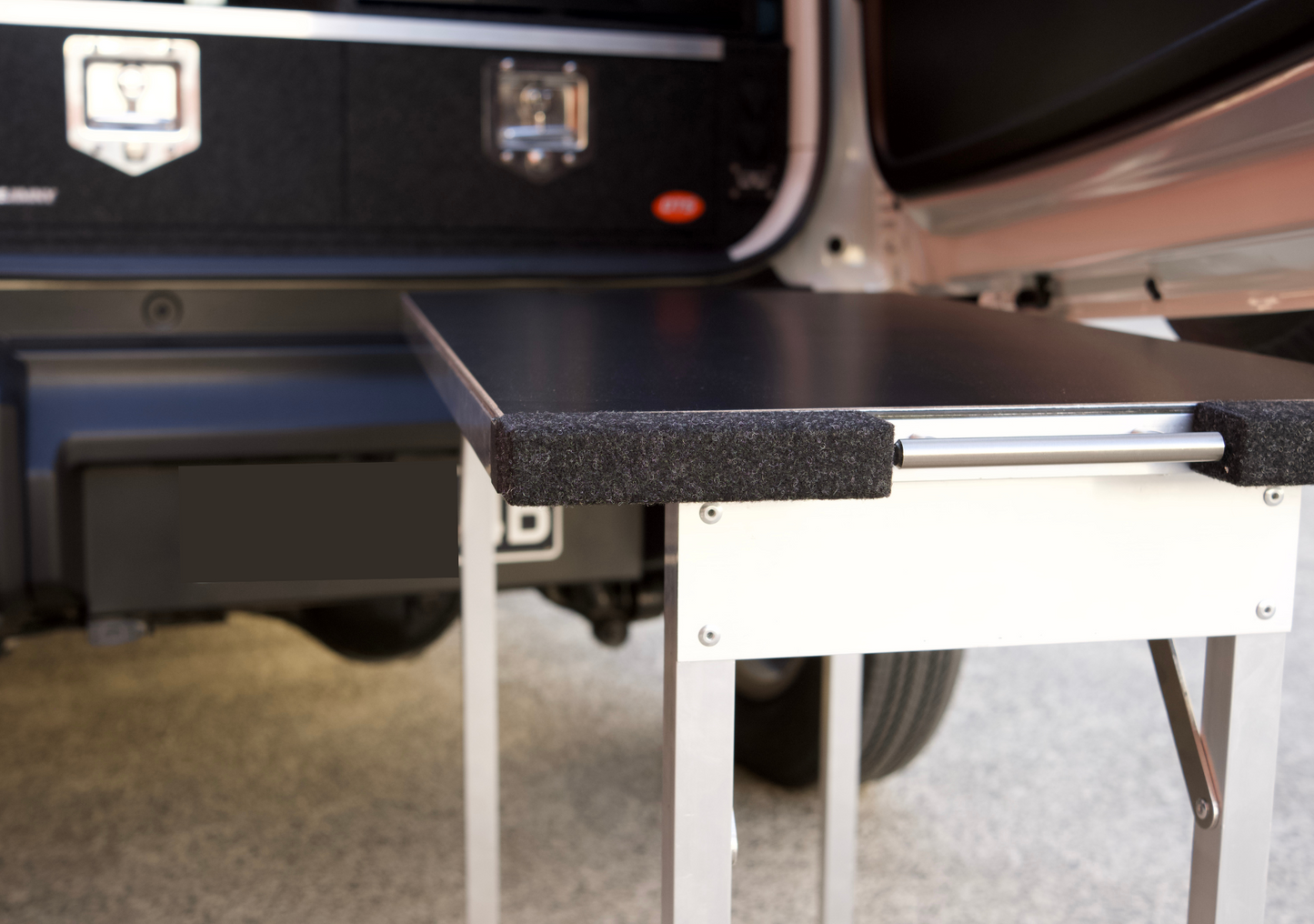 Suzuki Jimny XL pull-out table extended from vehicle with sturdy metal legs and black surface